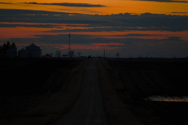 The sunsets near the small town of McLean Illinois in McLean County Illinois over a small farmstead and a narrow remote road spewing hues of red, orange, yellow and grey blue.\n\nImage is a stacked HDR (High Dynamic Range) processed images created from 3 base images.