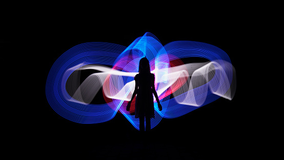 Woman silhouette against blue, white and red abstract backlight. Light painting photography. Long exposure.