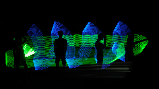 Human silhouette against green and blue abstract backlight on black background. Green light painting, long exposure photography