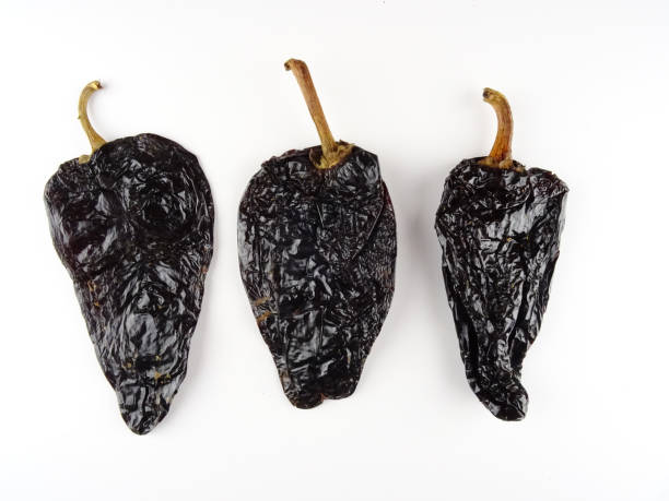 Isolated smoked dried peppers, Chile Ancho ,or dried Poblano pepper, Capsicum annuum, on a white background