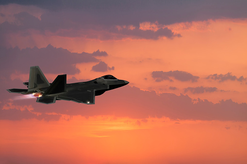 F-22 Fighter Jet flying with afterburner at sunset