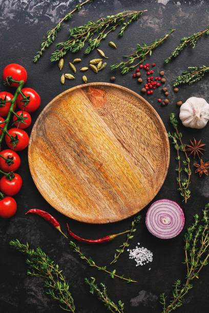 istock Flat lay empty wooden plate and frame of vegetables, herbs and spices. Top view, copy space. Different seasoning. 1136308164