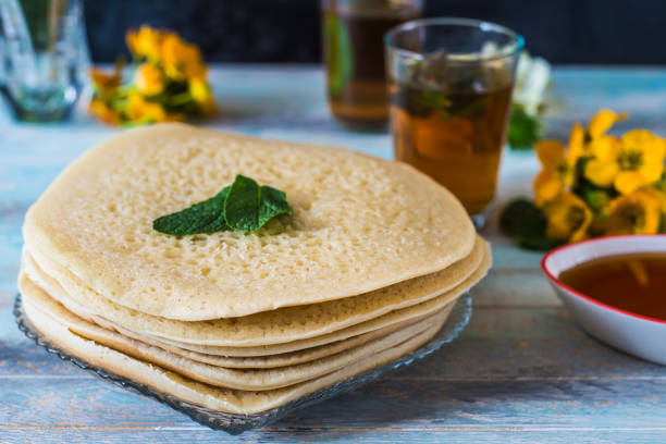 Moroccan pancakes Baghrir or crapes with 1000 holes served with honey, tea with nana , with background with flowers stock photo