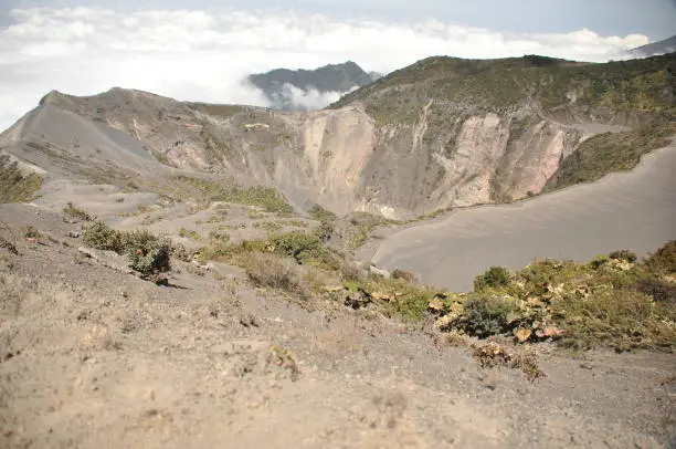 Photo of Irazu volcano in Costa Rica. Crater in clouds with protective barriers. Fragments of lava and pumice.