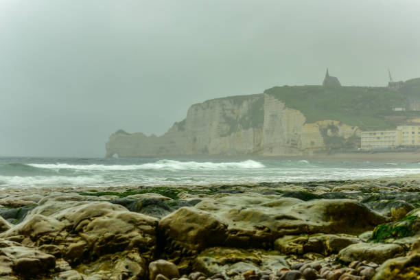 Spectacular natural cliffs Aval of Etretat and beautiful famous coastline on a cloudy day in Normandy, France, Europe.