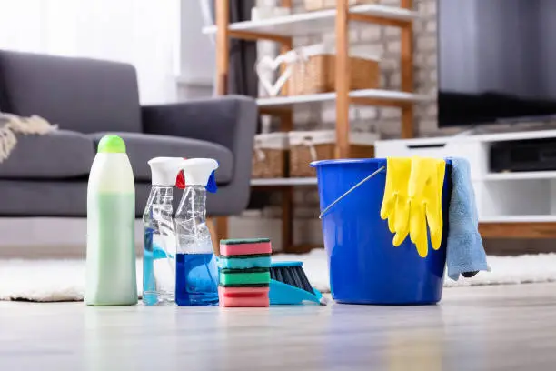 Close-up Of Cleaning Products And Tools On Hardwood Floor In Living Room