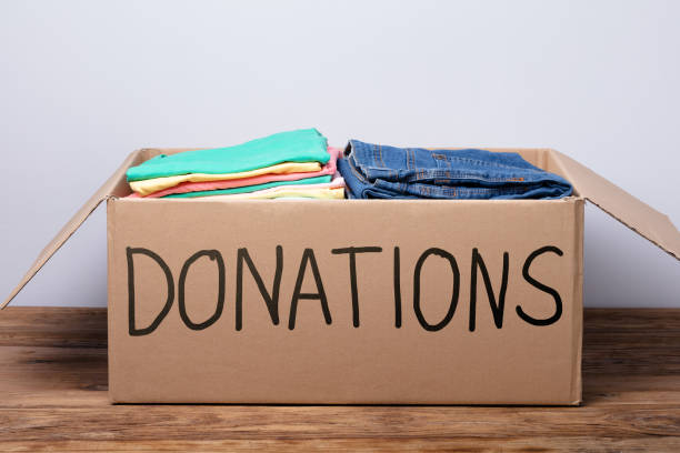 istock Donation Box With Clothes On Wooden Table 1136317115