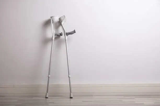 Close-up Of Pair Of Crutches Leaning Against Concrete Wall