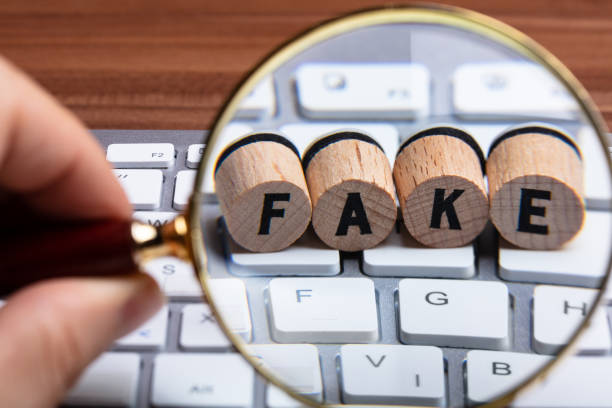 istock Hand Holding Magnifying Glass Over Wooden Cork On Keyboard 1136317674