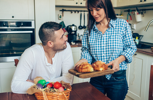 Happy family celebrating Easter with colored eggs and Easter bread on the table