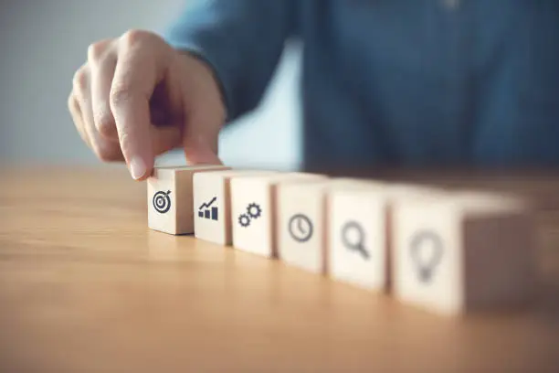 Photo of Businessman hand arranging wood block with icon business strategy and Action plan.