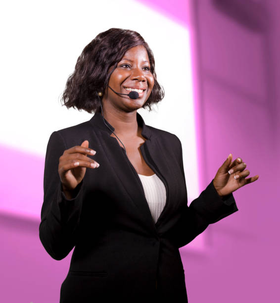 young attractive and successful black African American business woman with headset speaking in auditorium at corporate training event or seminar giving motivation and success coaching conference stock photo