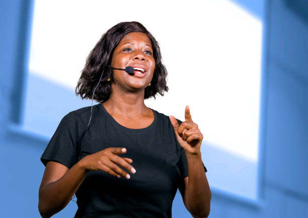 young attractive and successful black afro American entrepreneur woman with headset speaking in auditorium at corporate training event or seminar giving motivation and success coaching conference stock photo