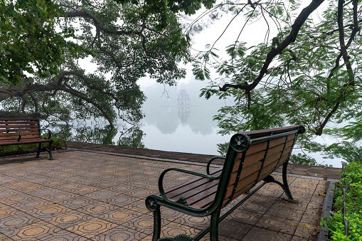 Autumn view of lake, tree, and bench on the bank of Hoan Kiem (Sword) lake in Hanoi, Vietnam.