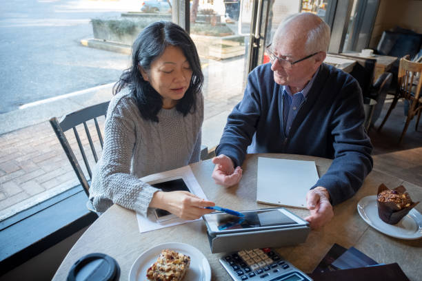 femme asiatique, homme aîné examinant l'information financière sur la tablette numérique - old book photos photos et images de collection