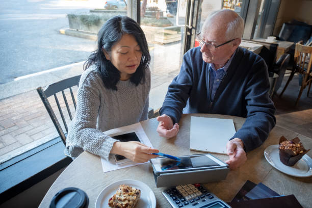 donna asiatica, uomo anziano che rivede le informazioni finanziarie sul tablet digitale - 401k retirement planning financial advisor foto e immagini stock