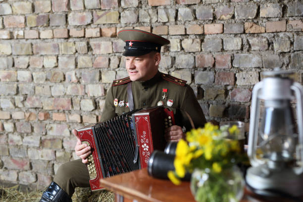 Historical reconstruction, a man in the form of a Soviet officer during the second world war . Plays the harmonica .