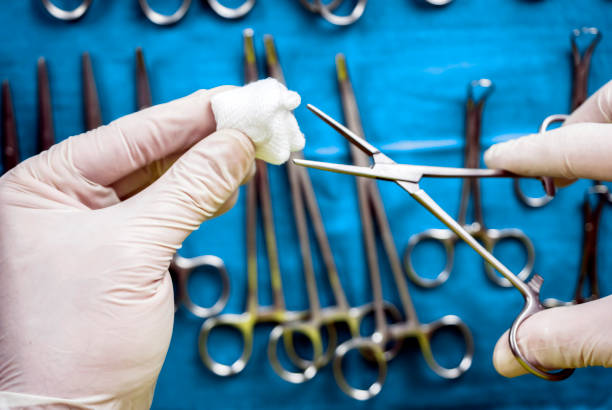 istock Surgeon working in operating room, hands with gloves holding scissors with torunda, conceptual image, horizontal composition 1136330347