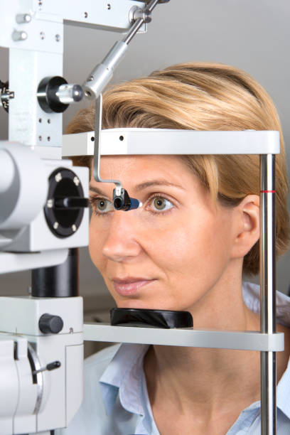 istock Mature Woman Looking Through Eye Test Equipment 1136331513