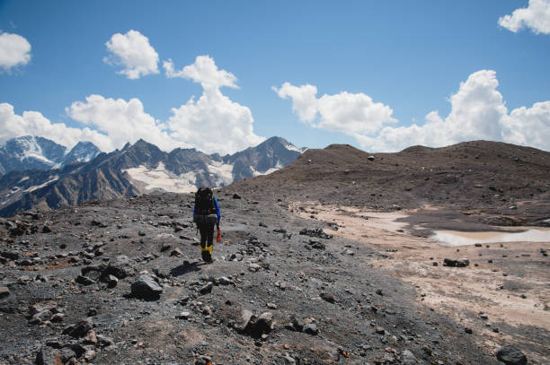 istock A mountaineer with a backpack walks in crampons walking along a dusty glacier with sidewalks in the hands between cracks in the mountain 1136335561