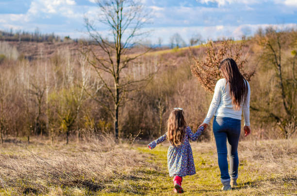 istock Mother and daughter walking in the nature back view 1136336040