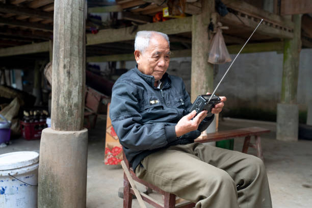 portrait of an elderly man listening to news from an old radio in Long Coc Commune, Xuan Son District, Phu Tho Province, Vietnam Long Coc Commune, Xuan Son District, Phu Tho Province, Vietnam-January 8, 2019: portrait of an elderly man listening to news from an old radio in Long Coc Commune, Xuan Son District, Phu Tho Province, Vietnam old person listening to radio stock pictures, royalty-free photos & images