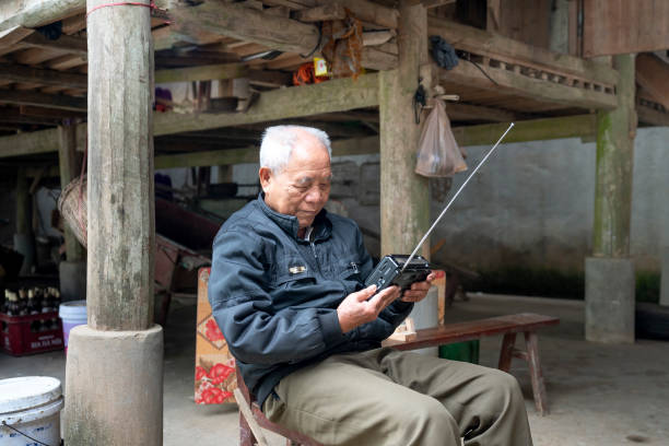 portrait of an elderly man listening to news from an old radio in Long Coc Commune, Xuan Son District, Phu Tho Province, Vietnam Long Coc Commune, Xuan Son District, Phu Tho Province, Vietnam-January 8, 2019: portrait of an elderly man listening to news from an old radio in Long Coc Commune, Xuan Son District, Phu Tho Province, Vietnam old person listening to radio stock pictures, royalty-free photos & images