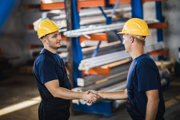 istock Mid adult manual workers shaking hands in aluminum mill. 1136340096