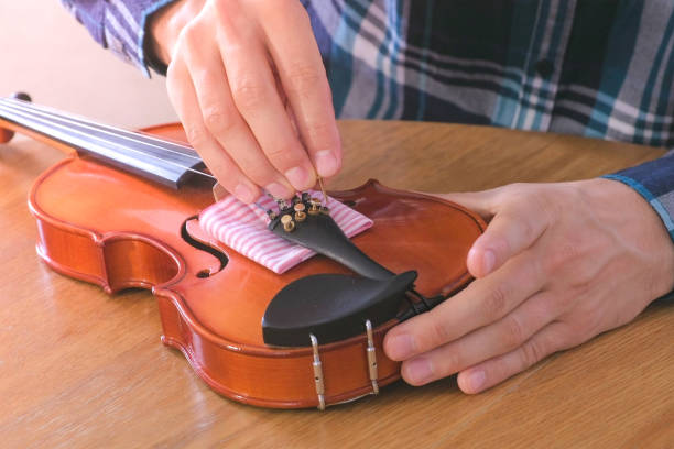 le mani ravvicinate del giovane in camicia a trecce riparano un violino seduto al tavolo. - workshop old fashioned old instrument maker foto e immagini stock