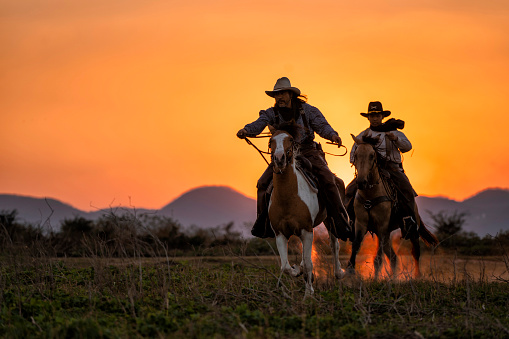 silueta de dos vaqueros paseo con los caballos bajo el atardecer photo