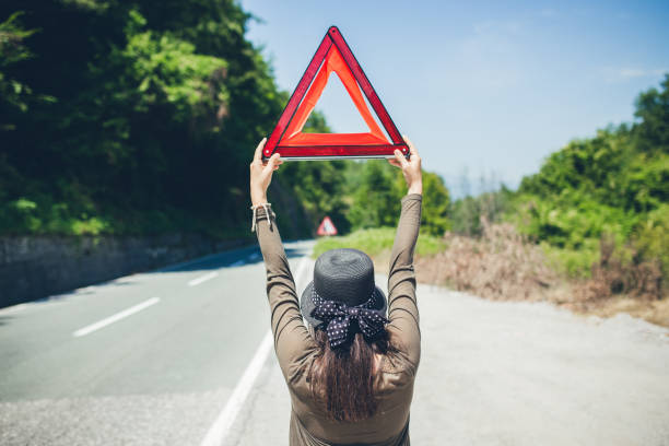 mujer que sostiene el triángulo del camino - car stranded women breakdown fotografías e imágenes de stock