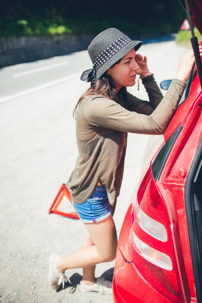 istock Woman standing by a broken down car 1136341380
