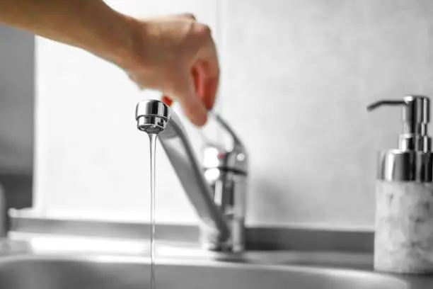 Photo of Hand opens the water tap. Close up