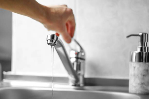 hand opens the water tap. close up - faucet imagens e fotografias de stock