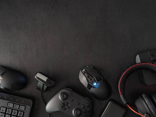 gamer workspace concept, top view a gaming gear, mouse, keyboard, joystick, headset, mobile joystick, in ear headphone and mouse pad on black table background. stock photo