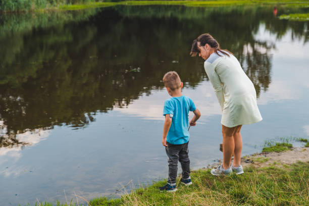 istock mother with son playing near lake water 1136348091