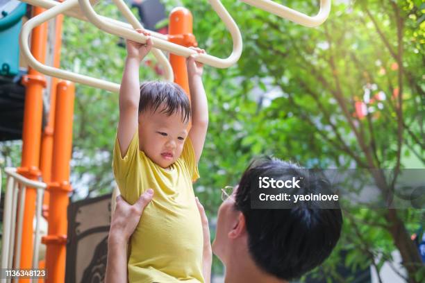 Father And Cute Little Asian 2 3 Years Old Toddler Baby Boy Child Having Fun Exercising Outdoor And Dad Help Catch Up On Monkey Bars Equipmen Stock Photo - Download Image Now