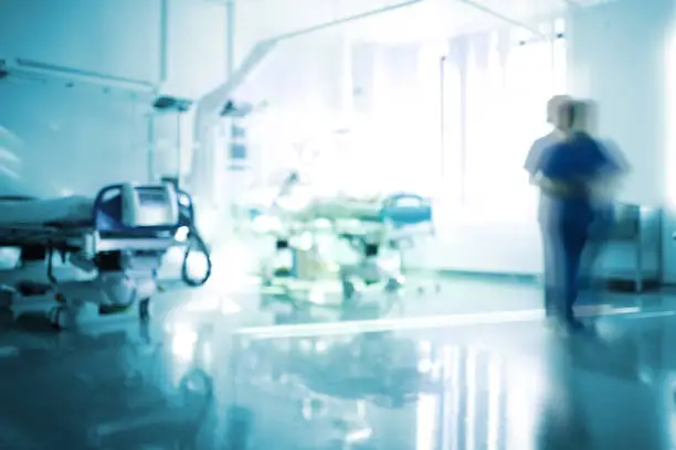 Blurred emergency room with walking staff, unfocused background.
