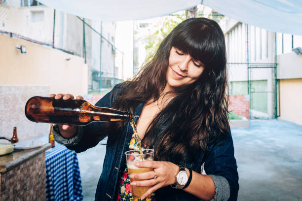 カップにビールを注ぐ若い女性 - beer bottle beer drinking pouring ストックフォトと画像