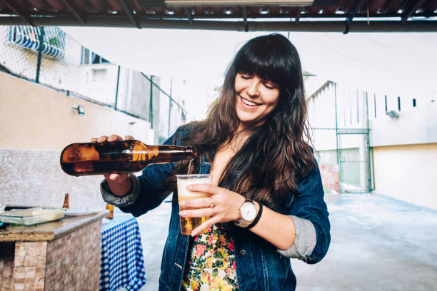 カップにビールを注ぐ若い女性 - beer bottle beer drinking pouring ストックフォトと画像