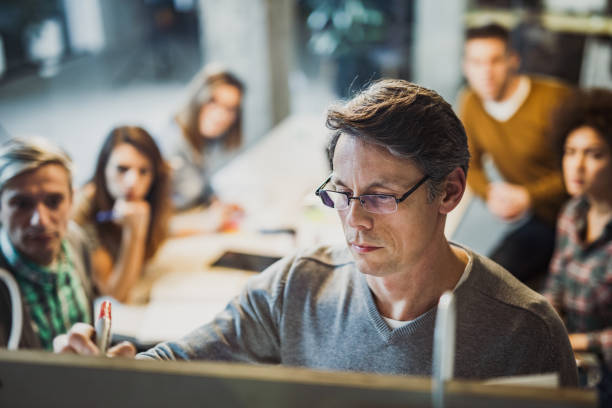 male manager writing plans to his team during presentation in the office. - writing whiteboard men businessman imagens e fotografias de stock