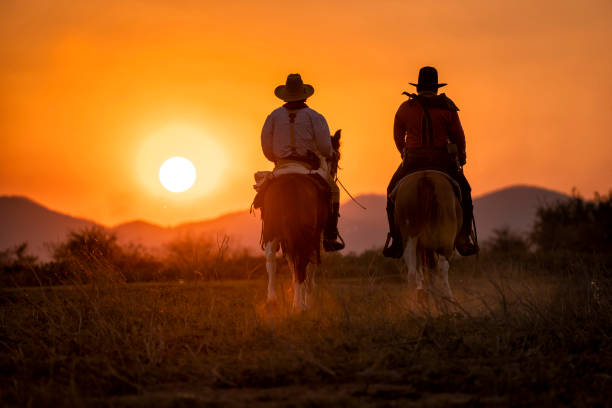 istock silhouette two cowboys ride with they horses under sunset 1136356521