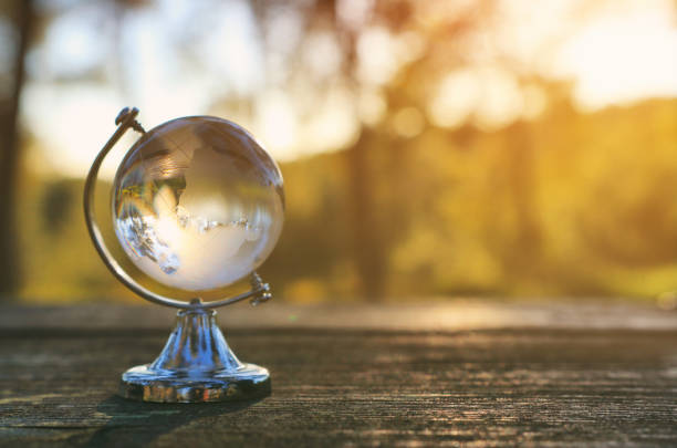 istock small crystal globe in front of sunset. travel and global issues concept 1136356713