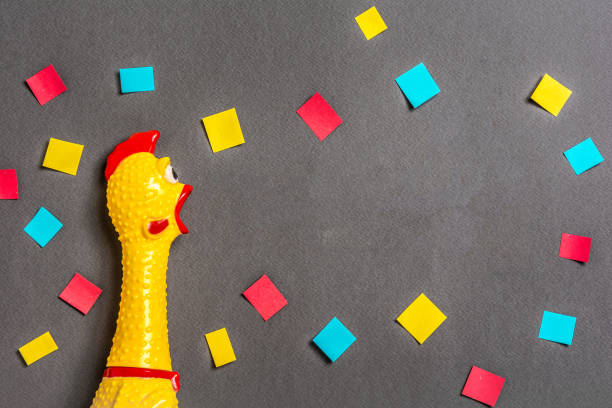 Squawking chicken or squeaky toy shouting representing a megaphone on dark background with confetti. Concept of message or announcement.