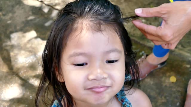 Mother combing to remove louse from little girl head