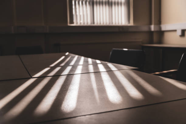 Beams of light cast across a table in an office's meeting room Beams of light cast through a window's vertical blinds and across a table in an office's meeting room. Belfast, Northern Ireland. Selective focus. dark window blinds stock pictures, royalty-free photos & images
