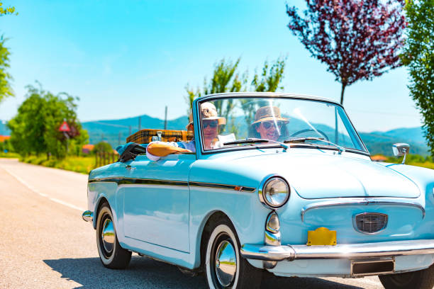 mature couple on a road trip with a vintage car - senior adult cheerful adventure discovery imagens e fotografias de stock