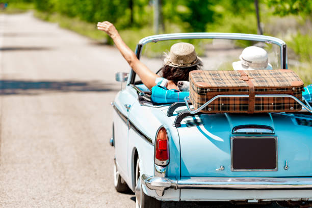 heureux couple mature portrait sur un road trip vacances conduisant une voiture vintage - move back photos et images de collection