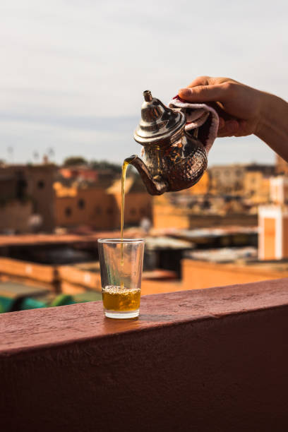 istock Pouring typical Morrocan fresh mint tea from a silver karraffe into a tea glass above the roofs of the Medina of Marrakesh (Marrakesh, Morocco, Africa) 1136363522