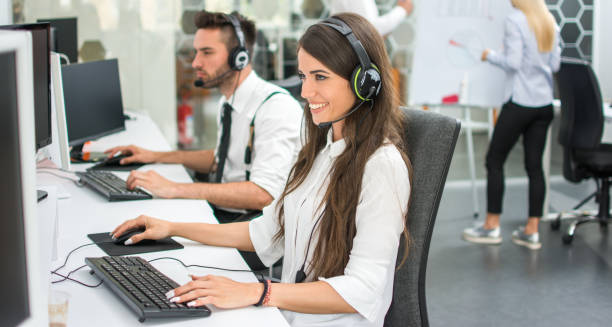 istock Cheerful customer support operators working in call center. Side view of smiling young business woman and business man talking with clients and solving problems on computers. 1136367294